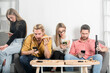 © Volodymyr - Friends sit together but all look at their phones. Group friends with social media concept. Group of people disconnected. Friends absorbed in devices. Technology silent distance.