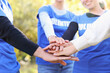 © New Africa - Group of volunteers stacking hands outdoors, closeup