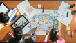 © InfiniteFlow - Top down aerial view of interior designer team choosing color from palettes while architect engineer planning house construction from tablet and project plan at table with building plan. Symposium.
