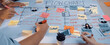© InfiniteFlow - A group of hands working together on a colorful flowchart using sticky notes and markers, showcasing collaboration and strategic planning in a modern office setting. SACTR