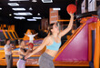 © JackF - Cheerful young European female in sportswear playing basketball while bouncing on colorful trampolines indoors in leisure sports center