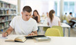 © JackF - Male student sits at table in library and works with books, printed literature, writes out theses and records key points, preparation for exam....