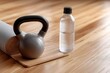 © Виктория Марьенко - Kettlebell, yoga mat, water bottle prepared for fitness session on wooden floor.