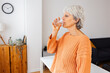 © Xavier Lorenzo - Side view of senior adult woman drinking a glass of water in the morning at home. Healthy life habit, lifestyle concept