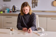 © Евгений Вершинин - Self reliant woman handles morning pills in peaceful kitchen setting, Woman with cerebral palsy diligently manages her daily medication routine independently at home