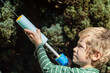 © milkovasa - Young boy playing with a water squirter toy in a sunny backyard