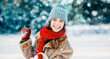 © Prostock-studio - A young woman is smiling joyfully while holding a heart shape made of snow. She wears a warm winter outfit with a hat and scarf. Fluffy snow falls around her, creating a winter wonderland scene.