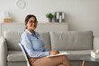 © Prostock-studio - A confident arab female psychologist is sitting in a modern office, writing in a clipboard. She smiles at the camera, creating a welcoming atmosphere during a mental health session.
