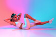 © Prostock-studio - A woman is engaged in a core workout, showcasing her strength and focus. She performs a bicycle crunch on a smooth surface under colorful lighting.