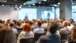 © liu - Modern conference room filled with attentive diverse audience listening focused on blurred professional speaker presenter man or college teacher presenting with projection screen in distance at front.