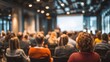 © liu - Modern conference room filled with attentive diverse audience listening focused on blurred professional speaker presenter man or college teacher presenting with projection screen in distance at front.