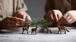 © Line - Hands arranging pine branch and deer figures on snow surface