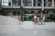 © qunica.com - A small team of colleagues stands together outside a contemporary office complex, reviewing papers and discussing plans, conveying collaboration, professionalism, and urban work life.