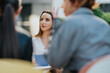 © qunica.com - A focused woman in a white top engages with coworkers in a contemporary office. The scene highlights professional dialogue, listening, and collaboration among a small group.