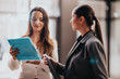 © qunica.com - Two people share a moment of teamwork in a contemporary office, examining a bright blue folder as they collaborate on a plan. A candid, constructive scene of business communication and partnership.