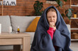 © Pixel-Shot - Sick young woman wrapped in blanket coughing at home