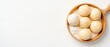 © Hryhor Denys - Small round pastries dusted with white powder in a wooden bowl on a white surface.