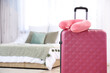 © Pixel-Shot - Neck pillow on suitcase in bedroom. Travel concept