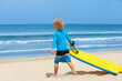 © Tropical studio - Portrait of little surfer boy with bodyboard have fun on beach, walk by white sand beach. Summer adventures, active families, parents and kids lifestyle, sports activities on school holiday with kids