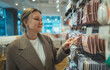 © M-Production - Woman Examining Accessories In Retail Store Shelf.
