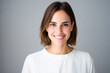 © Kowit - A smiling woman with shoulder-length hair, wearing a white top, poses in front of a neutral background, exuding warmth and confidence.