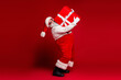 © deagreez - Santa in red costume lifts large gift in a festive studio scene for Christmas promotion and holiday cheer