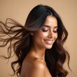 © Vadym - Young Indian woman smiles with eyes closed, her long dark hair blowing in the wind. She has radiant skin and appears content after a hair treatment.