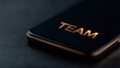© FocusFusion - Close-up of Smartphone With Metallic Team Lettering on Textured Surface