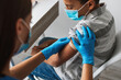 © Prostock-studio - A young African American boy sits indoors wearing a face mask as a medical worker administers a vaccine. The child is ready to receive protection against Covid-19 in a clinic environment.