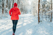 © Soloviova Liudmyla - Trail runner woman dressed bright red windproof jacket jogging picturesque snowy forest path during sunny frosty day. Sporty active people and winter training concept image.