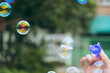 © Worldwide - Womans hand with blowing colorful soap bubbles in garden.