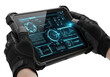© Viola - Rugged matte black industrial tablet with reinforced corners, glowing blue/green technical schematics on screen, held by tactical gloves, transparent studio background. Concept of critical data