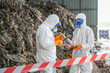 © BESTIMAGE - Two scientists in full protective gear conducting environmental sampling or research at a contaminated site with rocky terrain, safety equipment, and caution tape