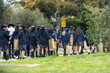 © Doublelee - A yellow 40 km/h school zone sign on a roadside in Australia, with a group of uniformed school students walking along a suburban footpath in the foreground. Concept of education and pedestrian safety