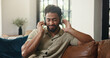 © Wess/peopleimages.com - Headphones, music and man on sofa in home listening to radio, playlist or song in living room. Happy, audio tech and male person streaming album for entertainment with chilling on weekend in house.