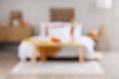 © Pixel-Shot - Interior of modern bedroom with soft bed, chest of drawers and pumpkins on coffee table, blurred view