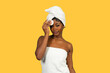 © EDUARDOIVAN - Black woman wrapped in towel using cotton pad for skincare