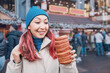 © EdNurg - Young woman happily holding and looking at a chimney cake, enjoying traditional street food at a festive European Christmas market during winter