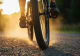 Cyclist rides a mountain bike on a rural path during golden hour, sunlight illuminating the dust kicked up by fast wheels
