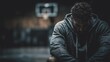 © jitharanat - Defeated athlete sitting on the ground with head down in muted tones conveying sadness and loss