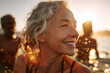 © EricMiguel - Sun-kissed smile: joyful senior woman laughing during golden-hour beach swim with friends, water droplets sparkling and carefree summer lifestyle at sunset