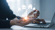 © HADI INCREDIBLE - Person using a laptop with digital house and chart overlays suggesting real estate growth and investment.