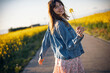 © Westend61 - Smiling woman holding flower in field during spring outdoors