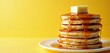© Vadym - Stack of fluffy pancakes with butter on top and syrup dripping down. Served on white plate against bright yellow background. Classic breakfast food.