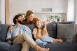 © Westend61 - Family laughing together while hugging on living room couch