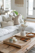 © Magdalena Wojaczek - Cozy living room vignette with textured pillows, natural wood coffee table, and decorative tray featuring candles and plant