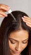 © Newleks - Woman applying liquid serum to her scalp with a dropper, performing a self care ritual for hair treatment and wellness, nourishing her roots and promoting healthy hair growth and strength