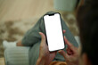 © Prathankarnpap - Close up of man hands holding a smartphone with white screen sitting on armchair