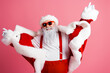 © deagreez - Santa in red suit with pink background dancing and posing for a festive photo wearing fur trim and glasses
