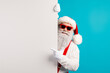 © deagreez - Santa peeks from behind a panel with red hat suspenders and blue background in festive Christmas mood